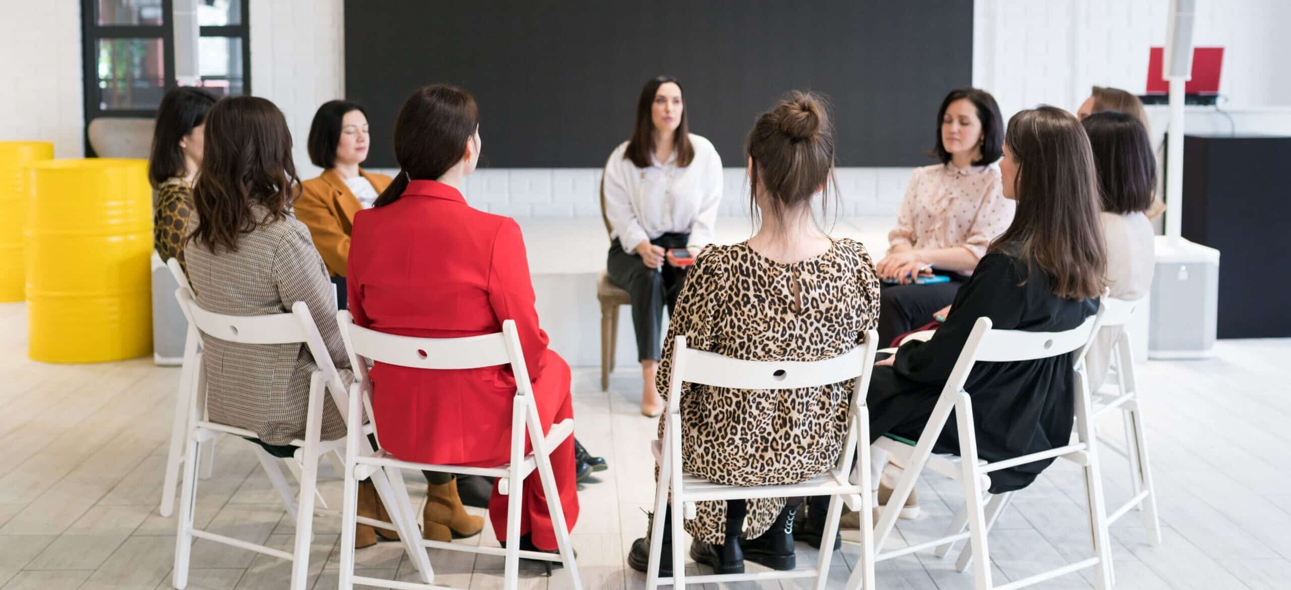 Woman in a group seated in a circle sharing her story.