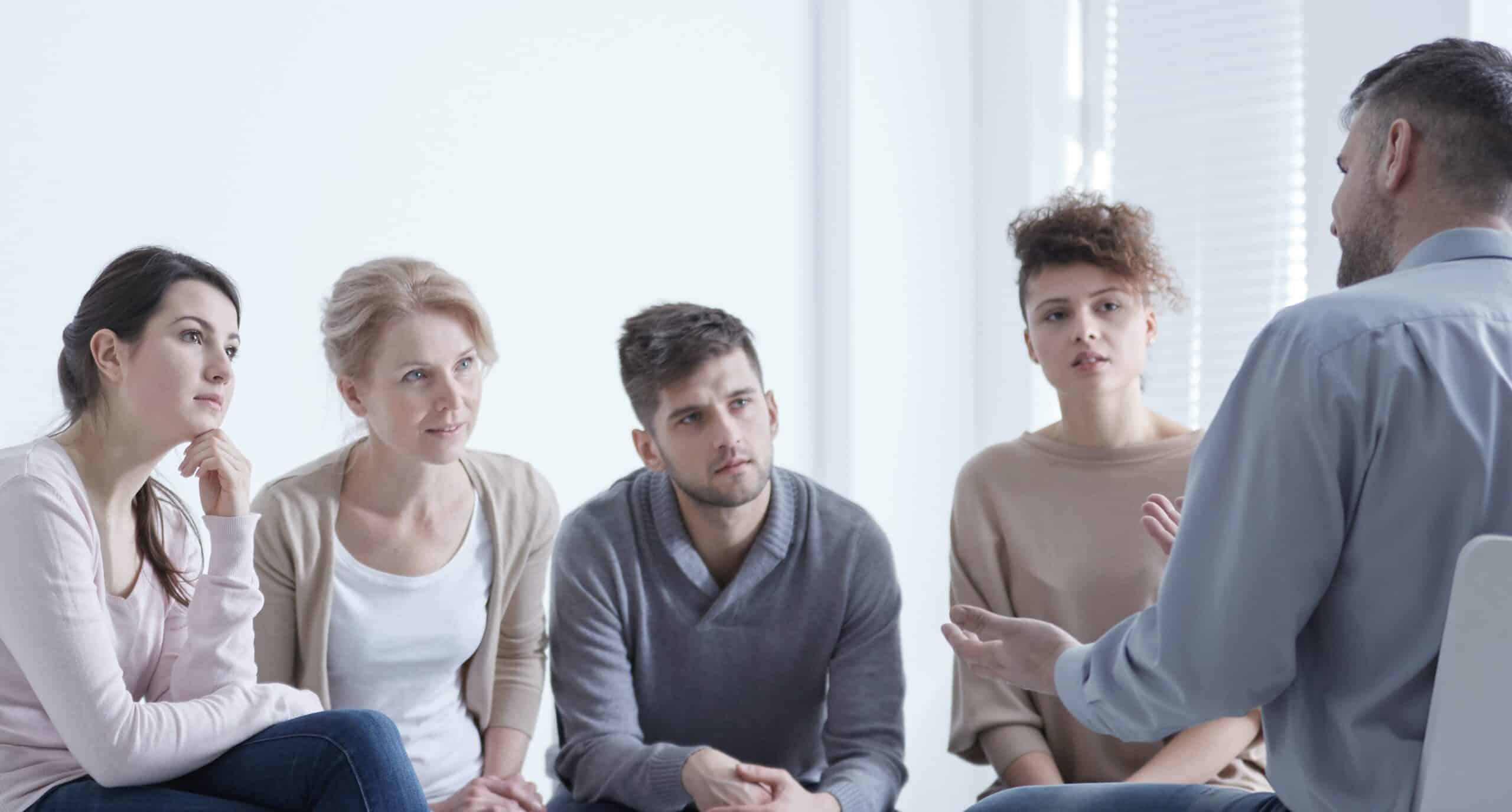 Man sharing his story to a group of people listening attentively.