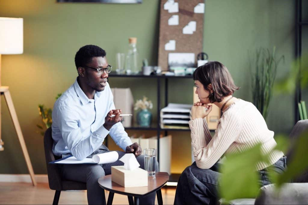 Image of a young woman sitting in a psychotherapy session with her therapist for the blog How Does Therapy Work by Soultenders