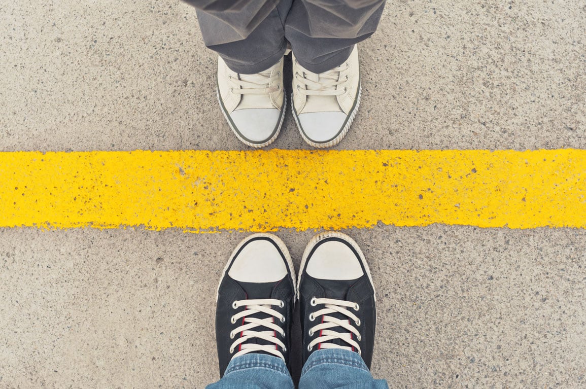 Two people standing on either side of a yellow line.