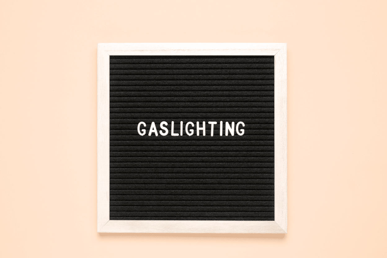 The word "gaslighting" on a letter board in a peach beige background.